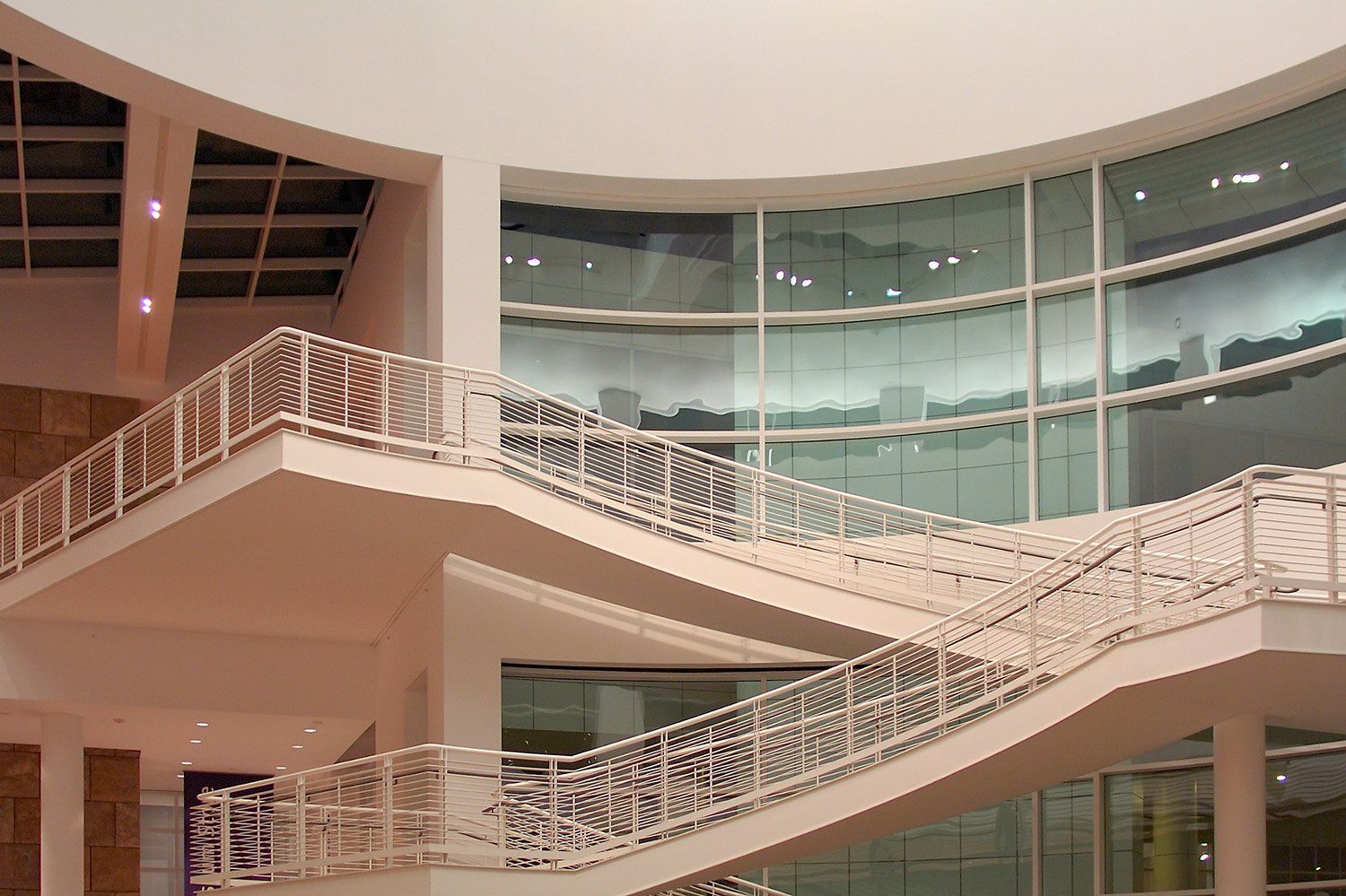 Stair landings wrapping a tall atrium with curved glass